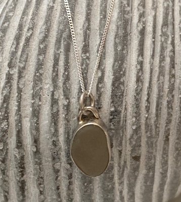 Seaglass necklace 

white/grey sea glass collected from dorset beaches. Set in a silver bezel setting. Hangs on a 16" silver chain. 


